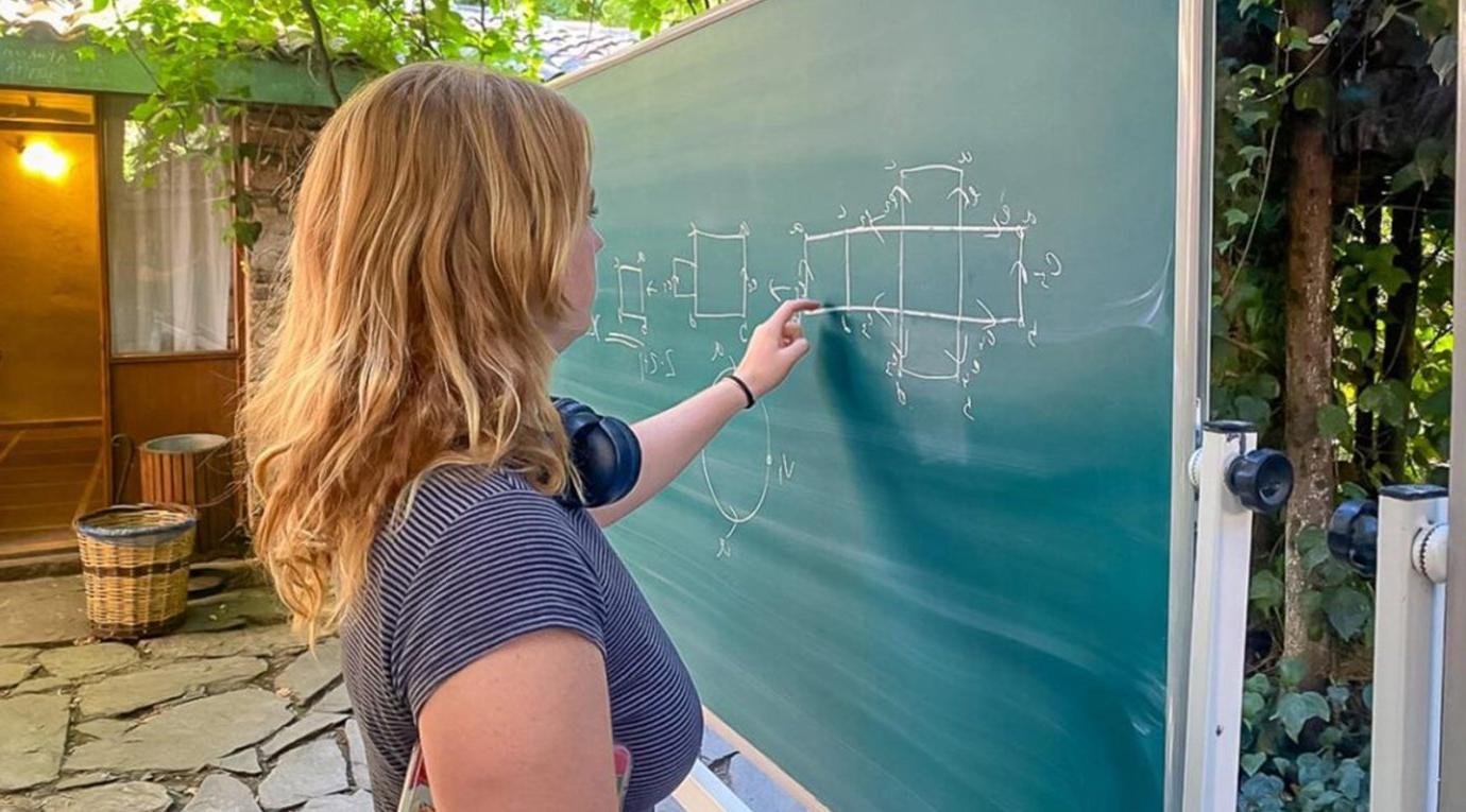 a math student solves a problem on a blackboard